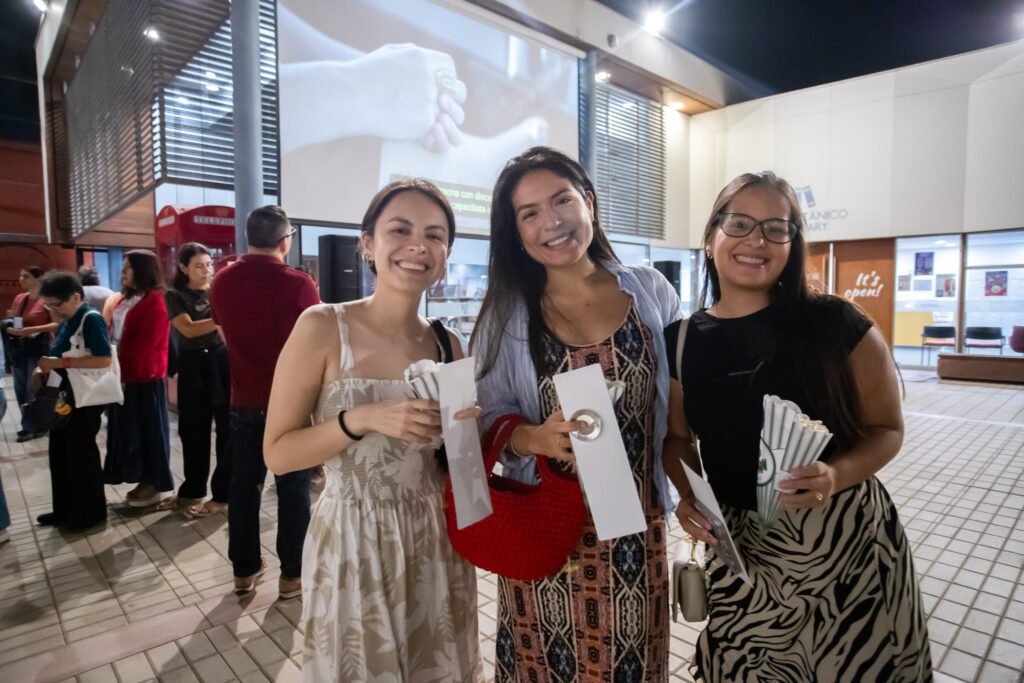 Foto de 3 mujeres sonrientes frente al espacio de proyección de la película