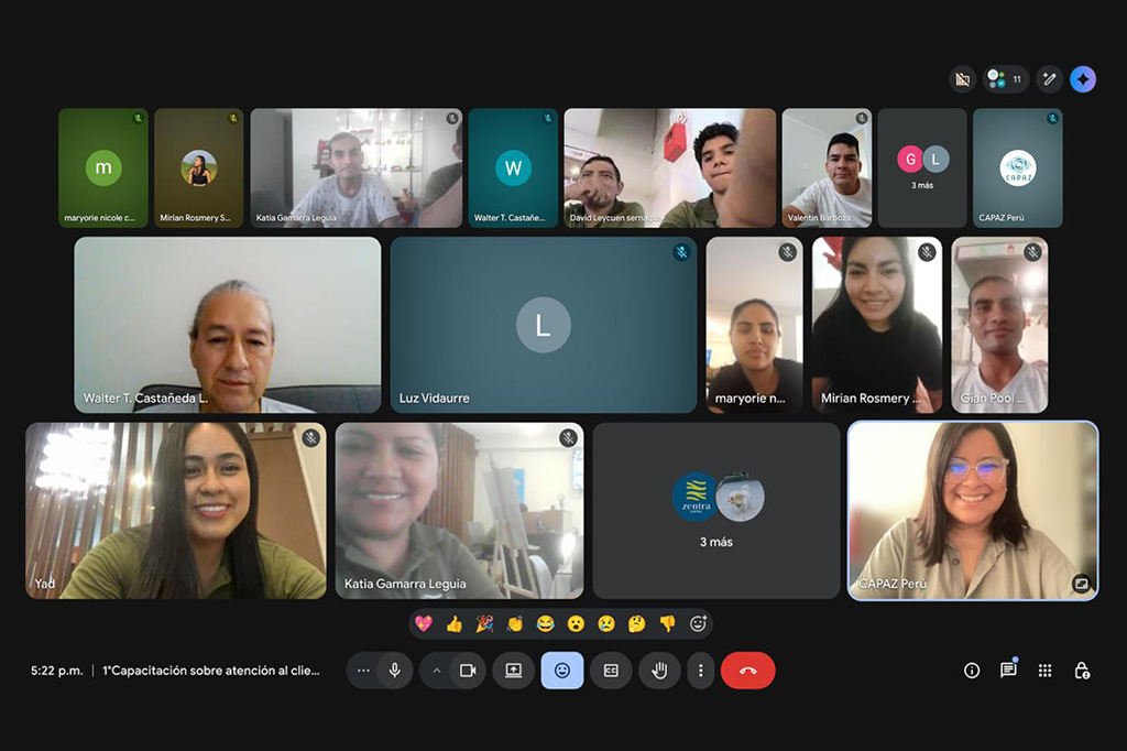 Captura de pantalla de una sesión virtual de capacitación por videollamada. Se ven varias ventanas con participantes conectados, algunos con cámara activada y otros solo con su icono de perfil. Hay personas sonriendo, conversando o escuchando. En la esquina inferior aparece la barra de controles de la videollamada con botones como micrófono, cámara, compartir pantalla y colgar. También se muestran algunos emojis de reacción y el nombre de la sesión en la parte inferior.