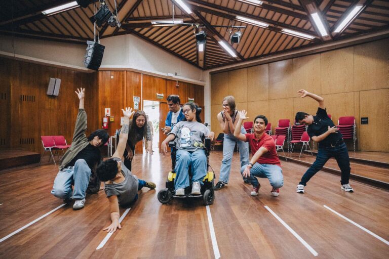 Grupo de artistas realizando una dinámica corporal en silla de ruedas y de pie.