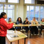 Facilitadora dirige un taller mientras las personas participantes escuchan.