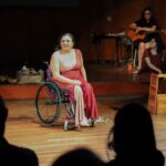 Artista en silla de ruedas durante una presentación teatral.
