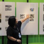 Facilitadora explica obras y fotografías expuestas en paneles.